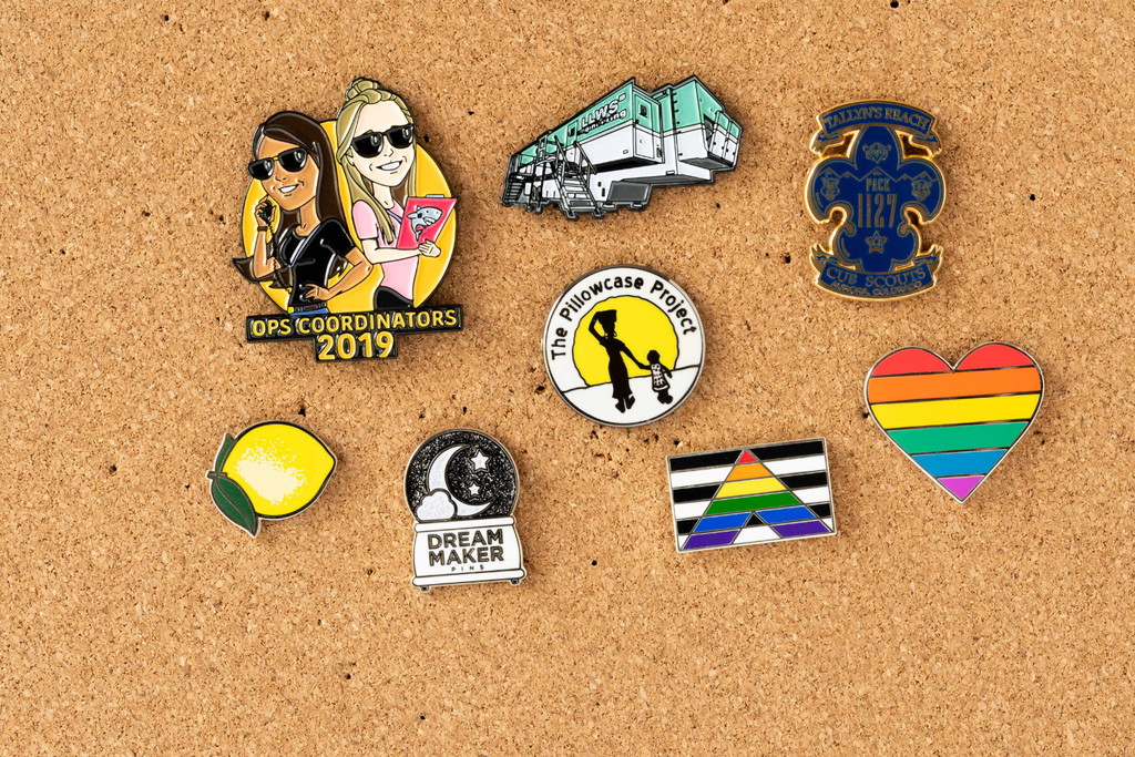 Dream Maker Pins custom enamel pins on a corkboard
