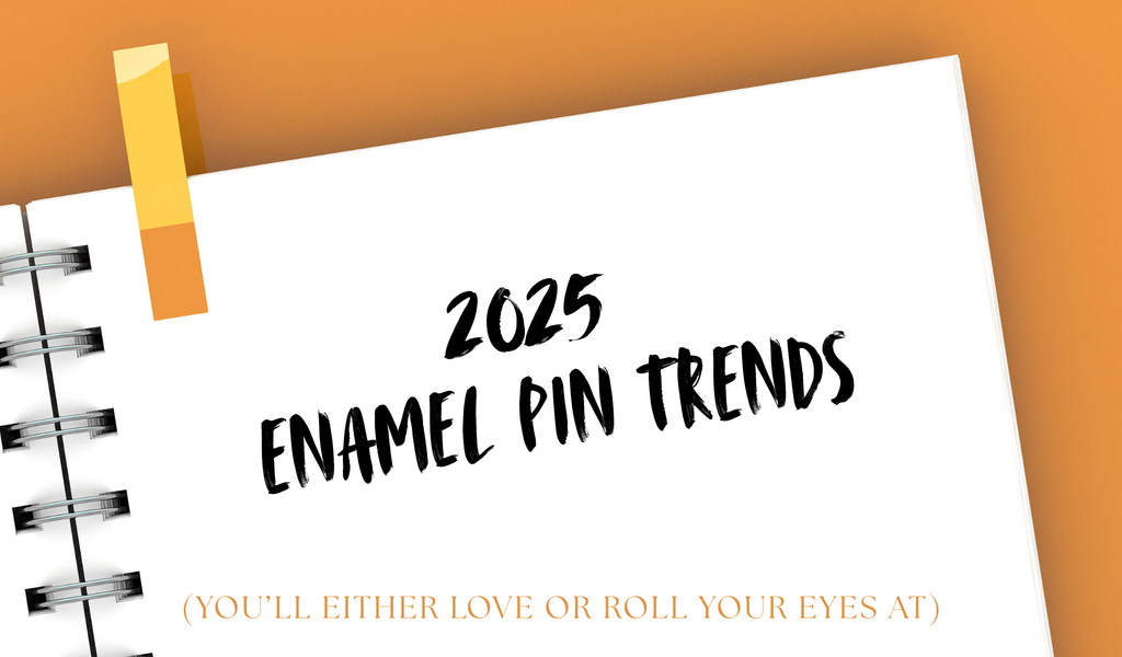 An open notepad with the text "2025 Enamel Pin Trends" written on top and  )You’ll Either Love or Roll Your Eyes At) on the bottom of the page