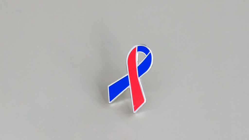 red and blue awareness ribbon enamel pin on gray background