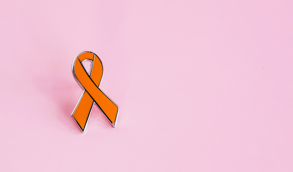 Orange awareness ribbon enamel pin on pink background