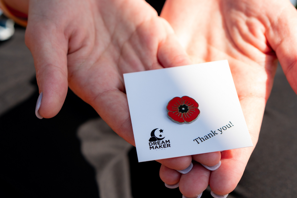 Red poppy pin on a pin card being held in a woman's hands