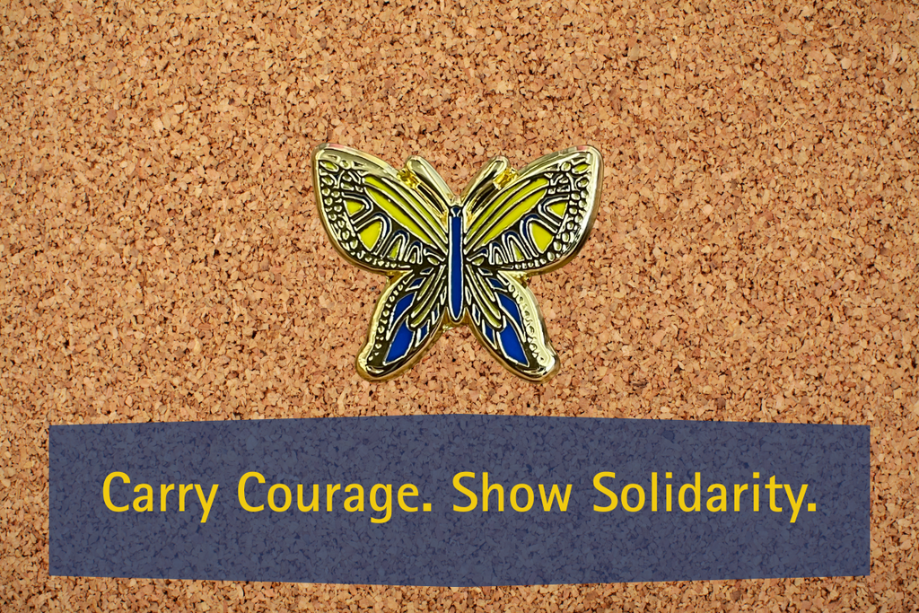 blue & yellow butterfly pin on a cork board with carry courage. show solidarity on it. 