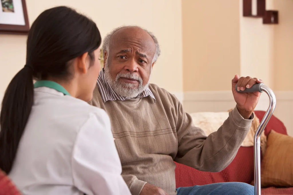 Older Black man patient with a cane talking to a doctor
