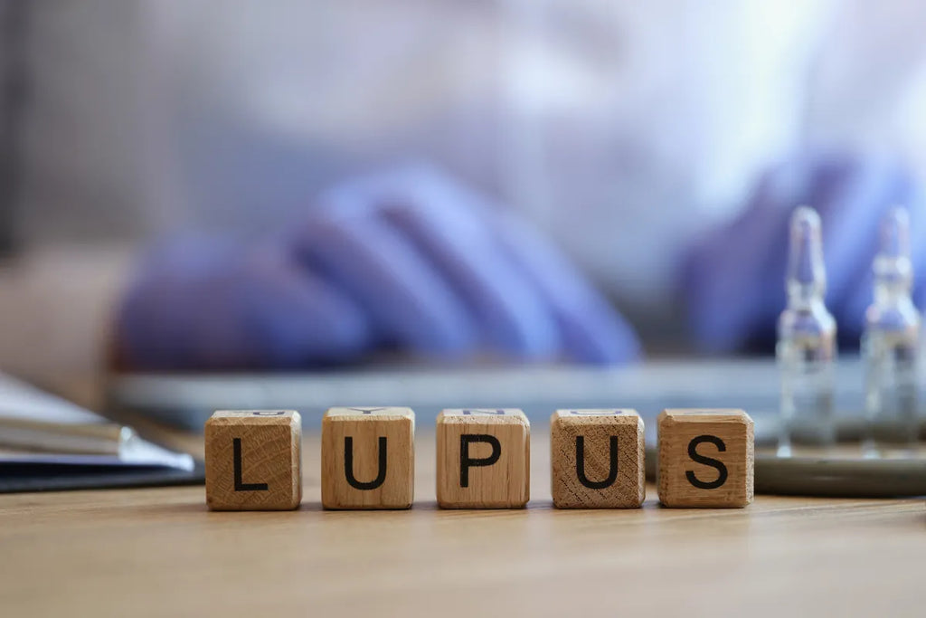 wood blocks spelling the word lupus with a medical person's hands and meds in the faded background